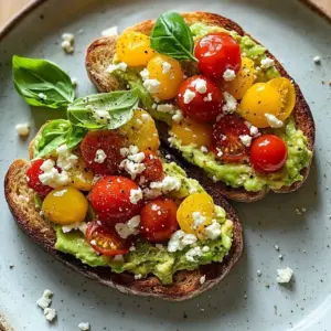 Avocado toast topped with feta cheese and fresh tomatoes on a wooden plate.