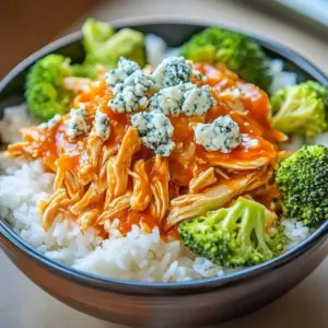 A delicious spicy buffalo chicken bowl garnished with fresh vegetables and sauce.